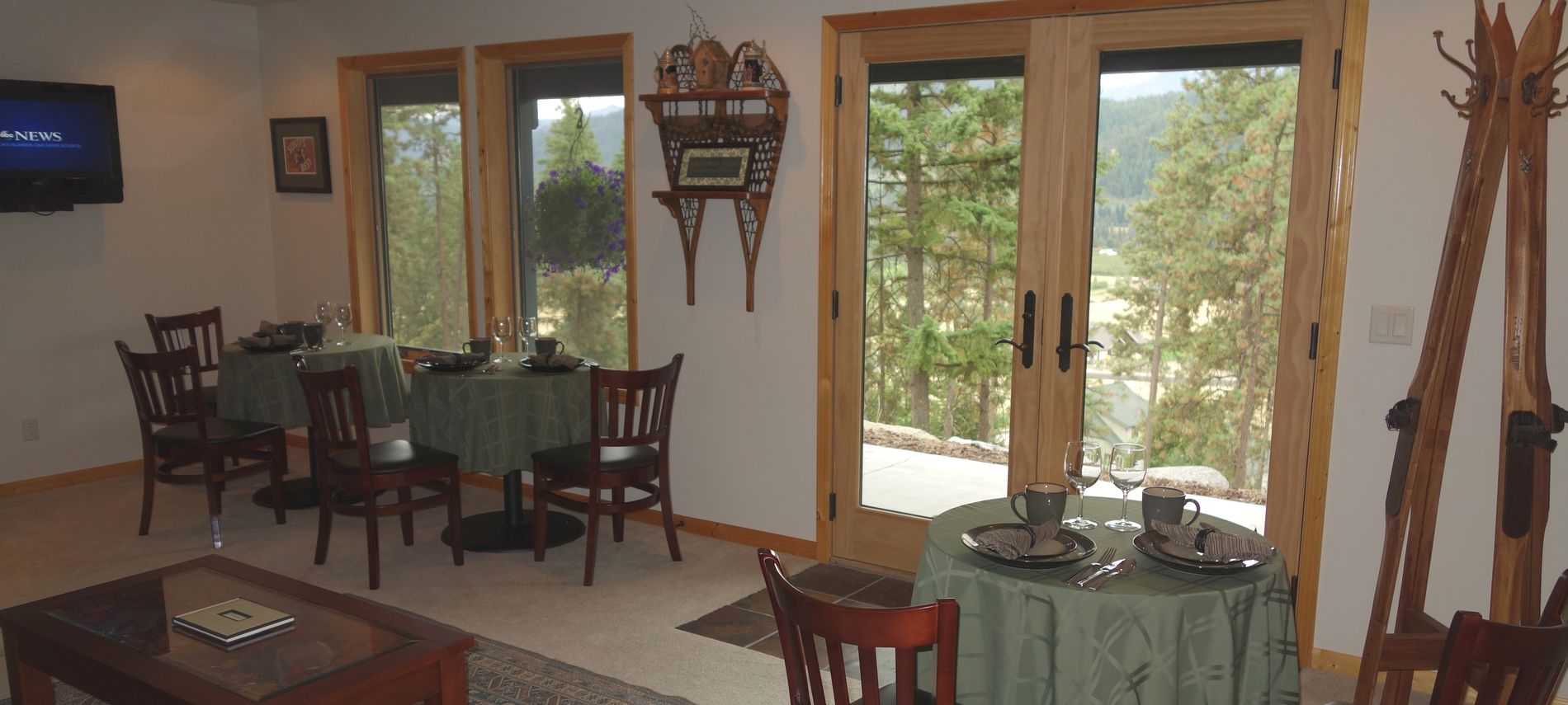 Interior of dining room showing exterior view of green trees and purple mountains.