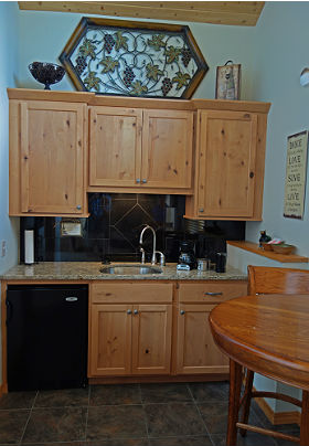 Interior of the room showing cabinets, sink, table and refrigerator.