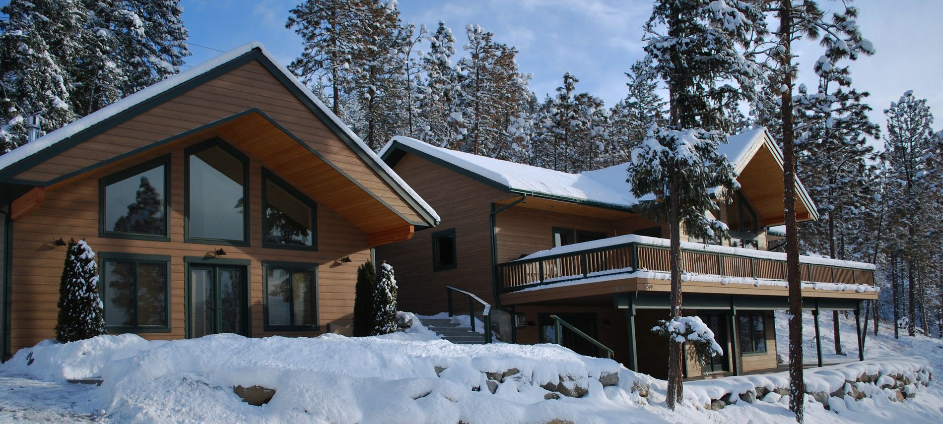 Exterior view of Inn showing house, deck and trees covered in white snow.