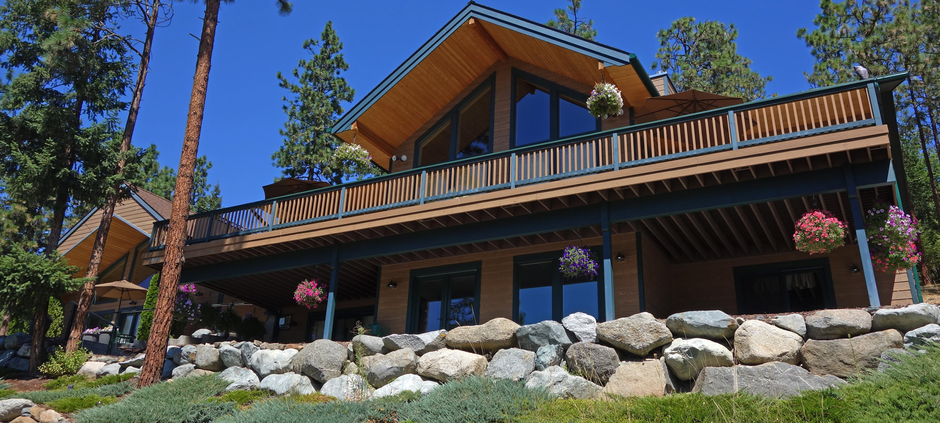 Summer exterior view of the Inn showing brightly colored flower baskets and blue sky.