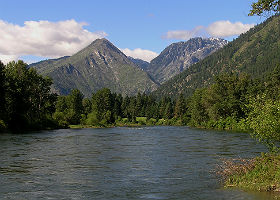 View of flowing river showing green mountains and blue water.